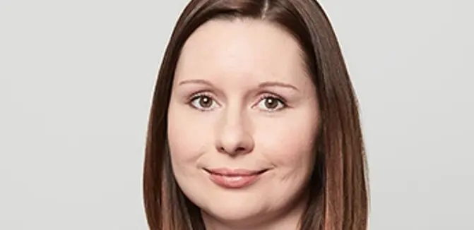 Maria Zisser hat schulterlanges Mittelbraunes Haar und braune Augen. Sie trägt eine hellblaue Bluse und einen hell grauen Blazer.