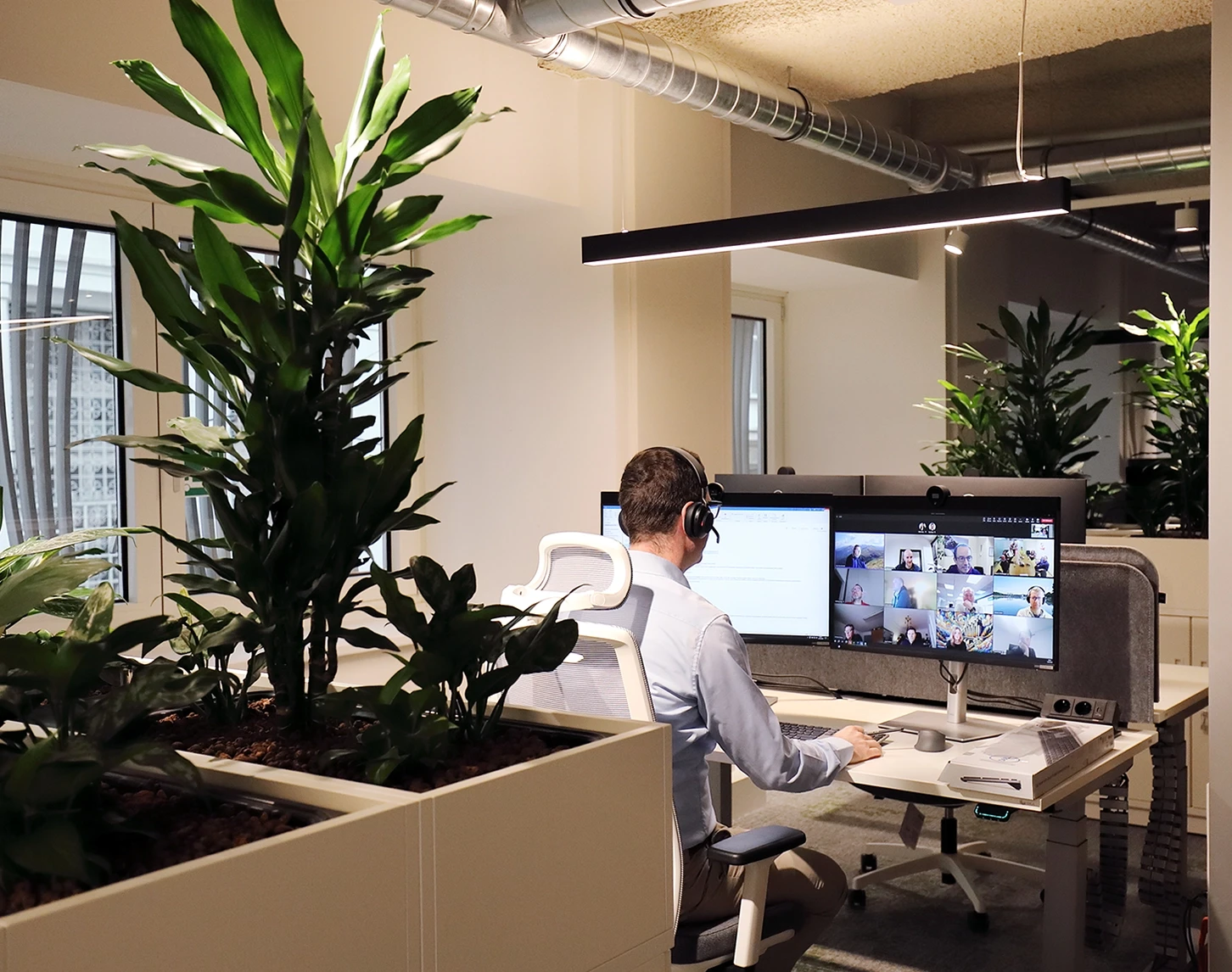 The photo shows VERBUND's Open Spache office. We look over the shoulder of a colleague who is in a team meeting. The office is bright and there are plants everywhere to ensure a good indoor climate.
