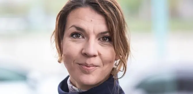 Die VERBUND-Mitarbeiterin trägt ihr mittelbraunes Haar zusammengebunden. Sie hat braune Augen und lächelt in die Kamera.