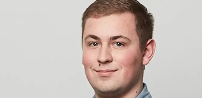 Florian Pazour hat hellbraunes kurzes Haar. Er lächelt in die Kamer und trägt eine mittelblaues Hemd.