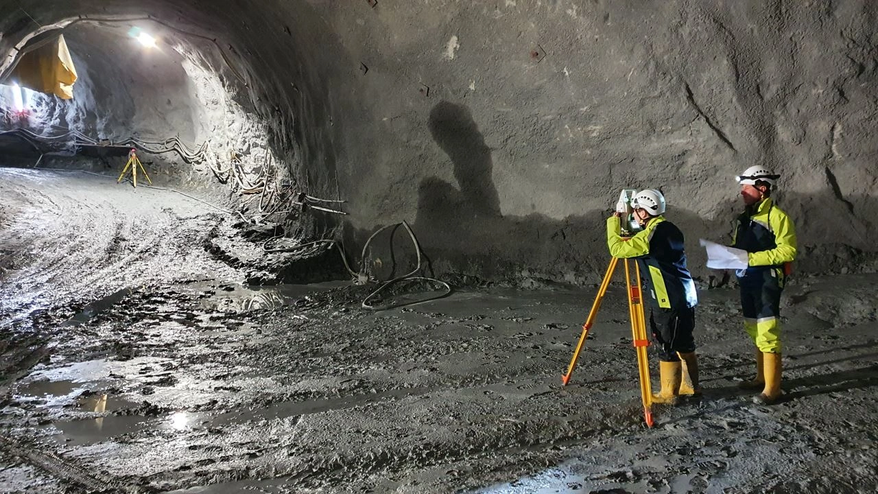 Wir beobachten zwei VERBUND-Mitarbeiter bei der Vermessung eines Stollen im Zuge einer Revitalisierung eines Wasserkraftwerks. Beide tragen Sicherheitskleidung und Helme.